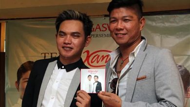 Dua pria berpose dalam sebuah acara musik sambil memegang sampul album