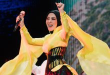 Syahrini tampil di panggung mengenakan busana kuning saat bernyanyi.